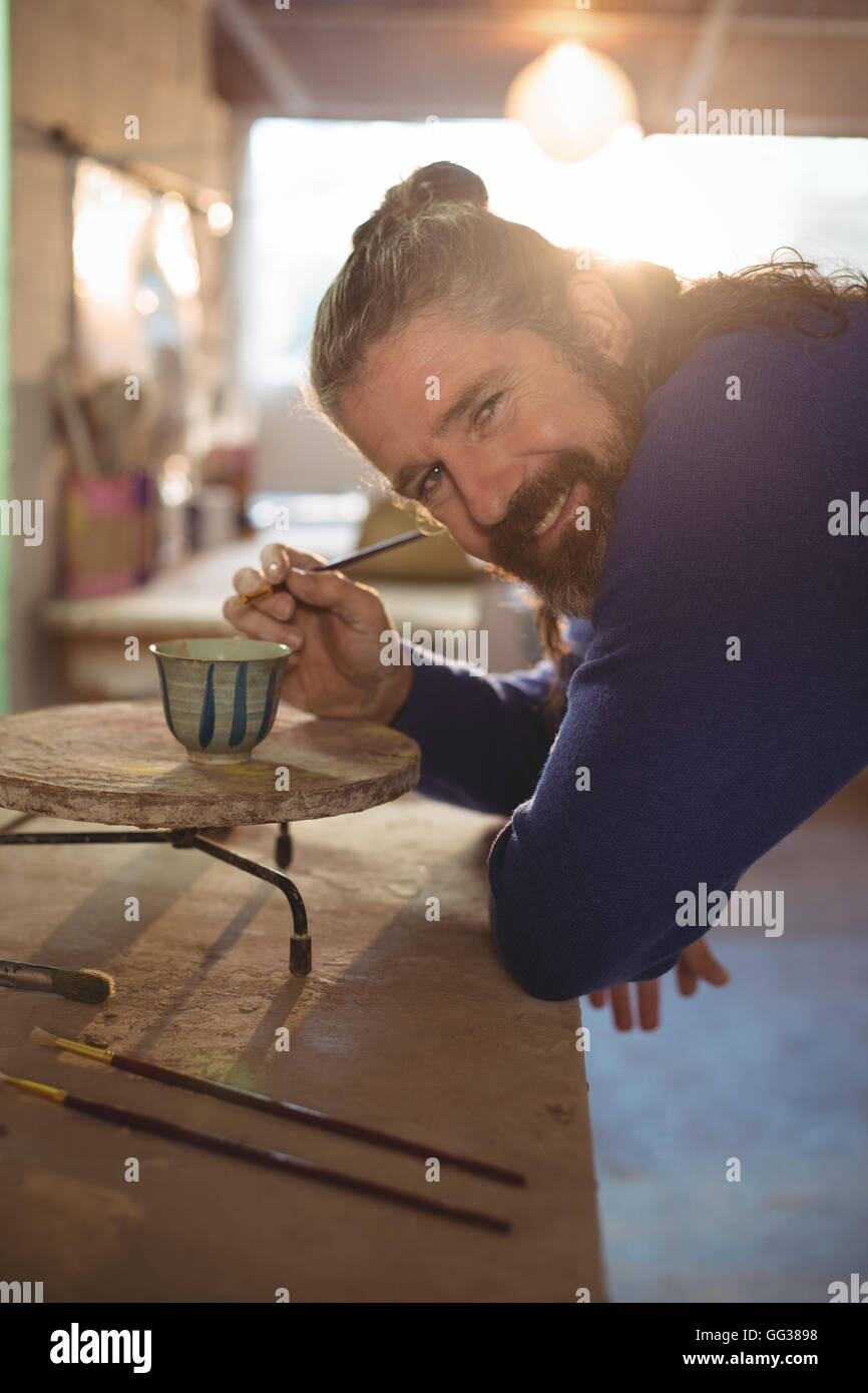 Smiling male potter painting on bowl Stock Photo - Alamy