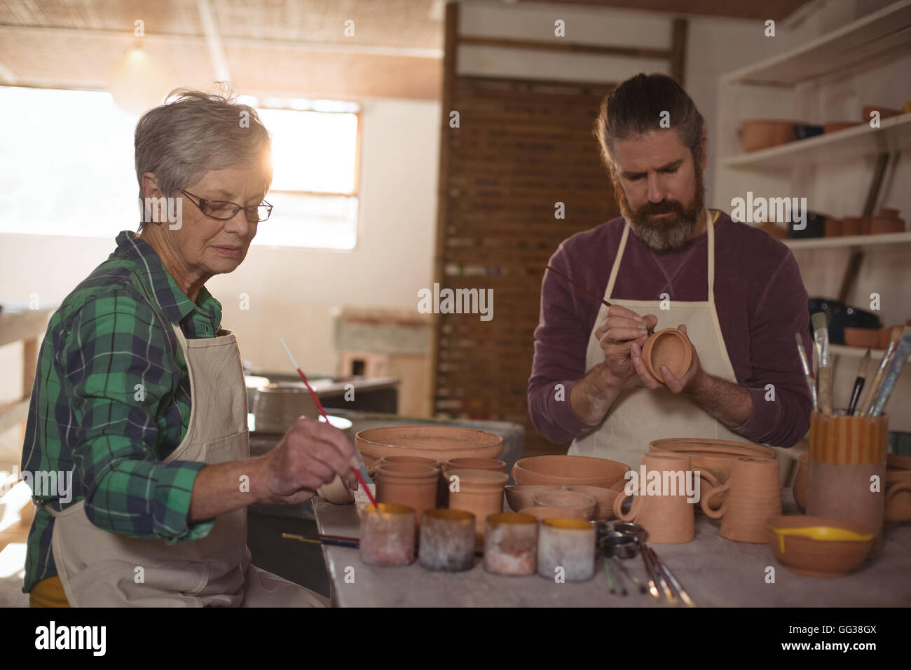 Male and female potter painting pots Stock Photo - Alamy