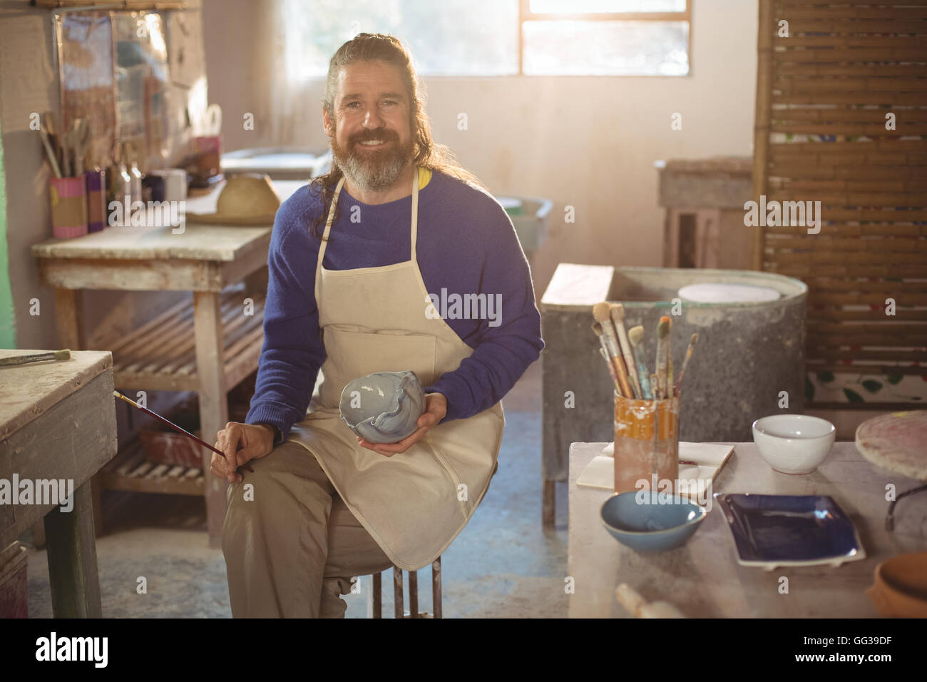 Smiling male potter painting on bowl Stock Photo - Alamy