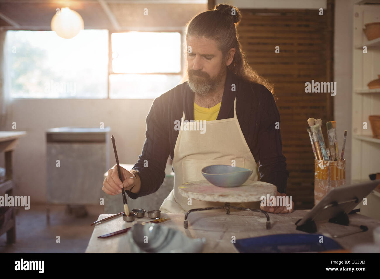 Attentive male potter painting on bowl Stock Photo - Alamy