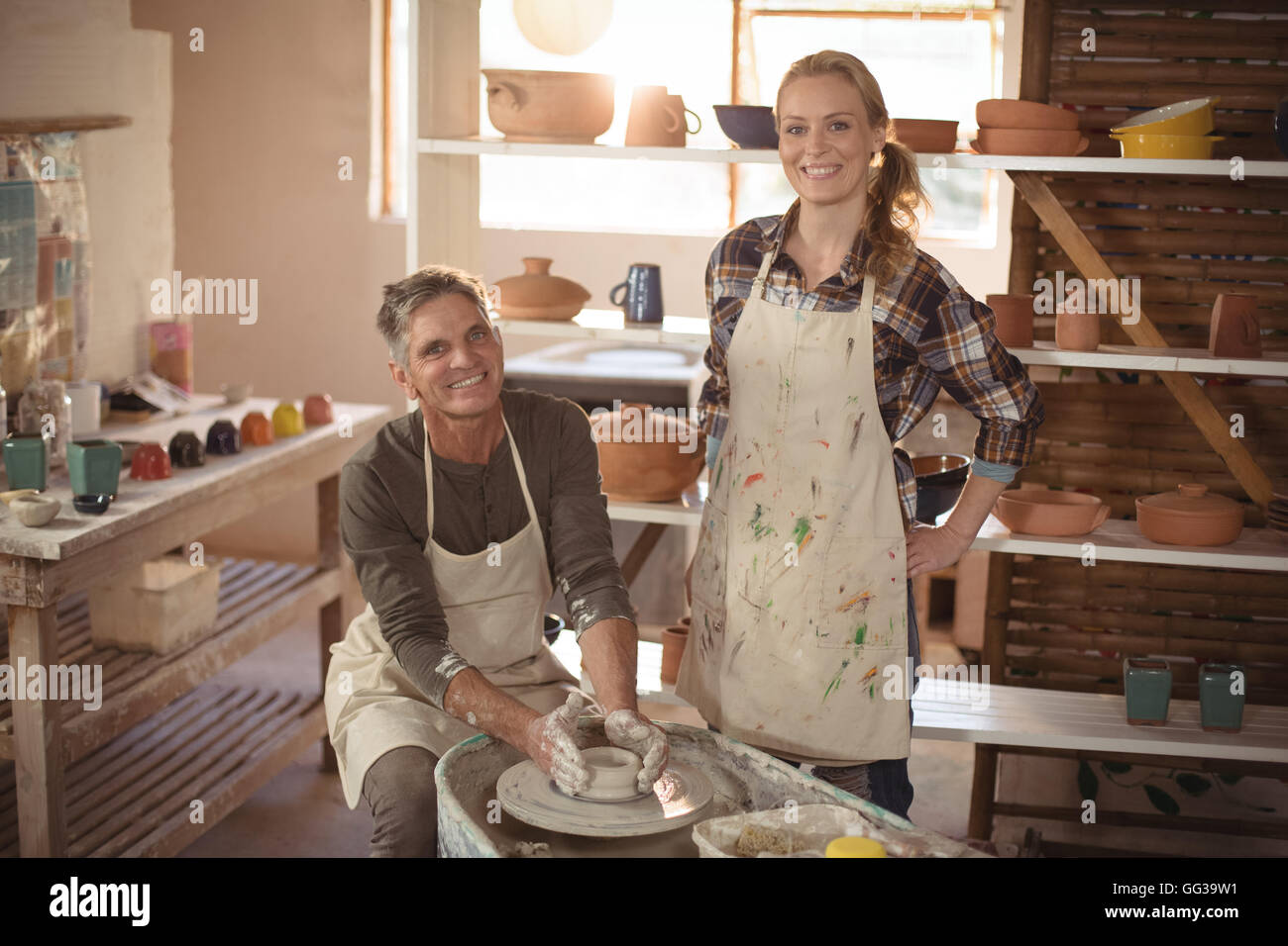 Male potter assisting female potter in pottery workshop Stock Photo - Alamy