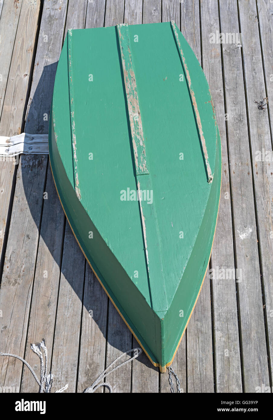 The hull of a green painted plywood skiff upside down on a deck. Stock Photo
