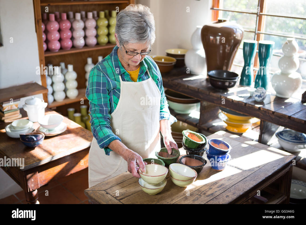 Female potter arranging bowl on worktop Stock Photo