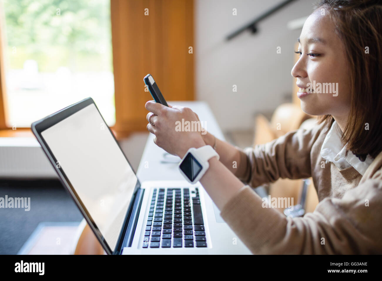 Young woman text message on mobile phone in classroom Stock Photo