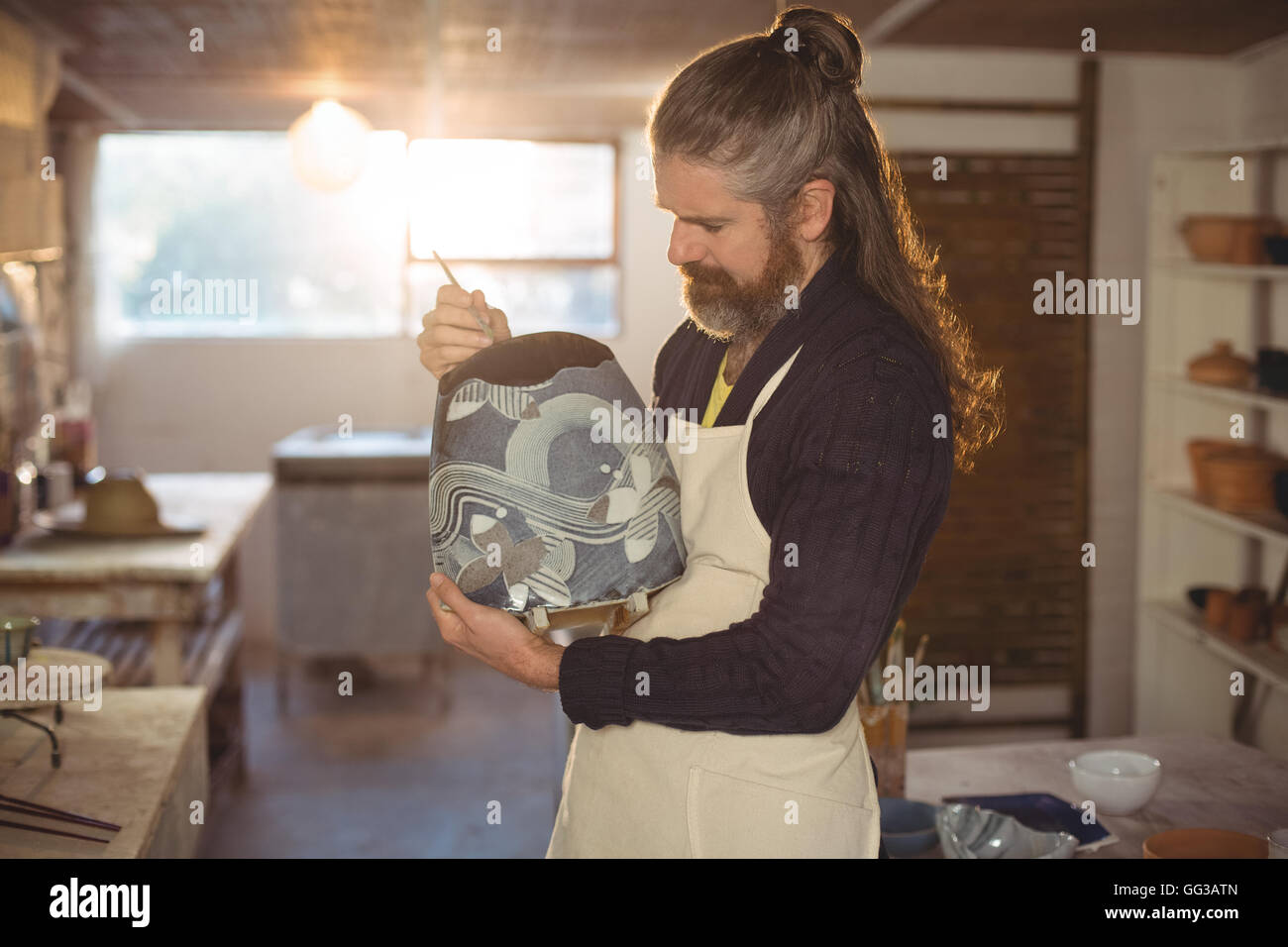 Attentive male potter painting on pot Stock Photo - Alamy
