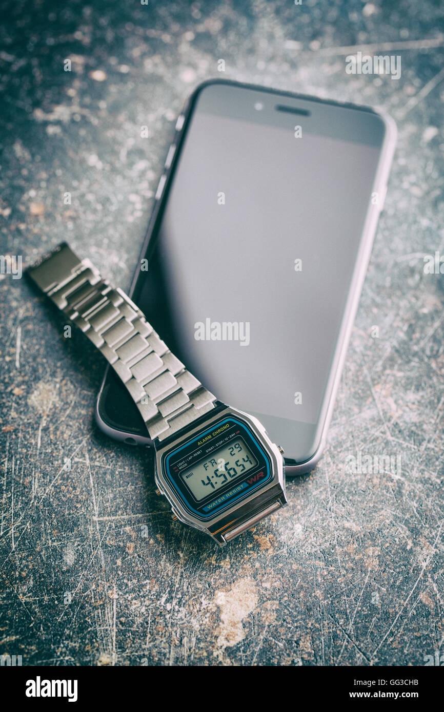 Digital watch and cellphone on old background. Vintage filter. Stock Photo