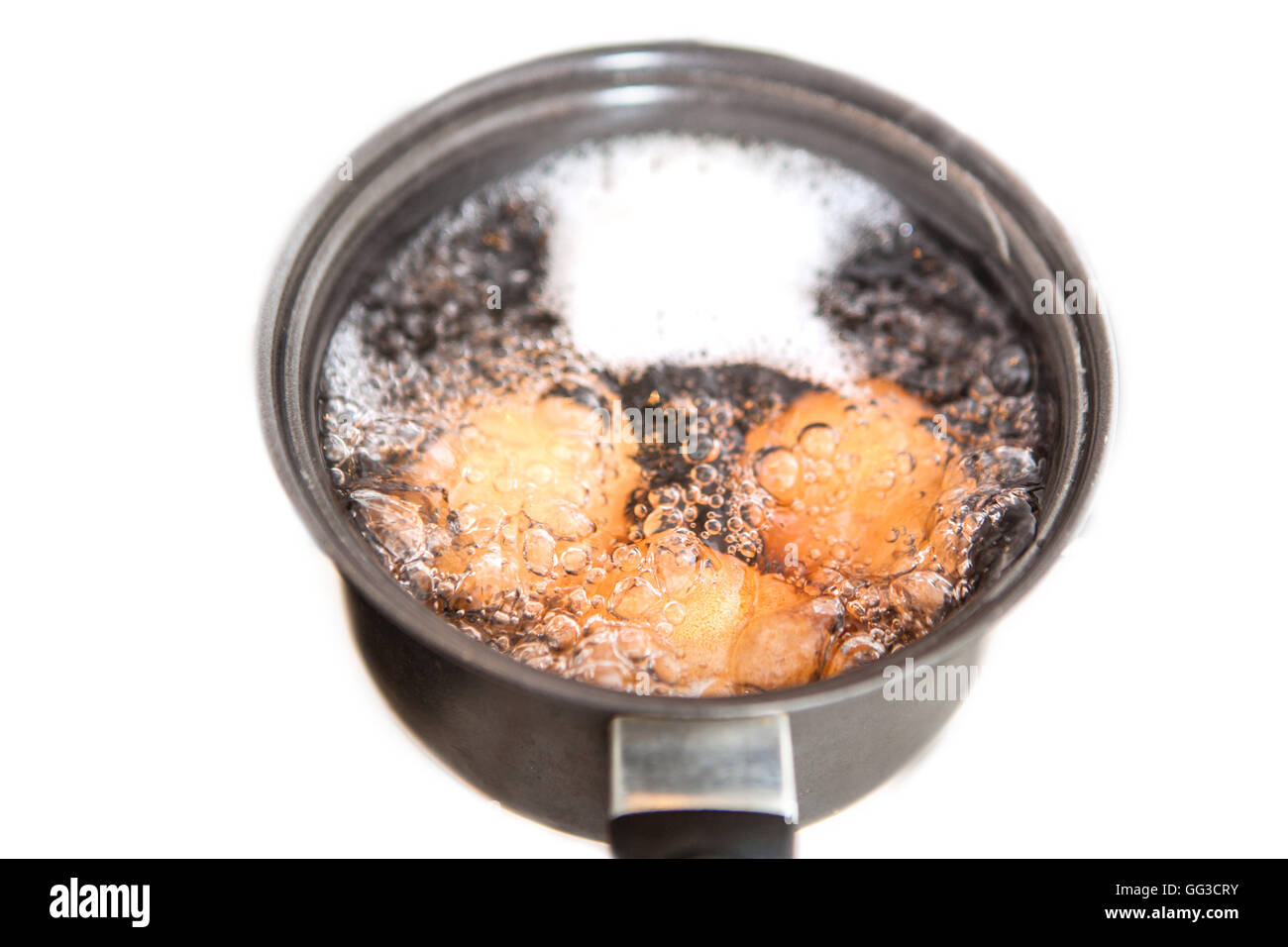 Eggs in boiling water in pan on electric hob Stock Photo