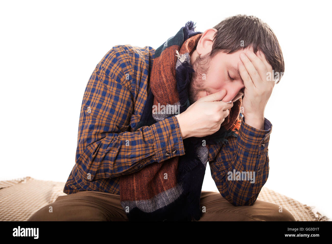 Closeup portrait of sick young man student, worker, employee with allergy, germs cold, blowing his nose with kleenex, looking very miserable unwell, isolated on white background. Flu season, vaccine Stock Photo