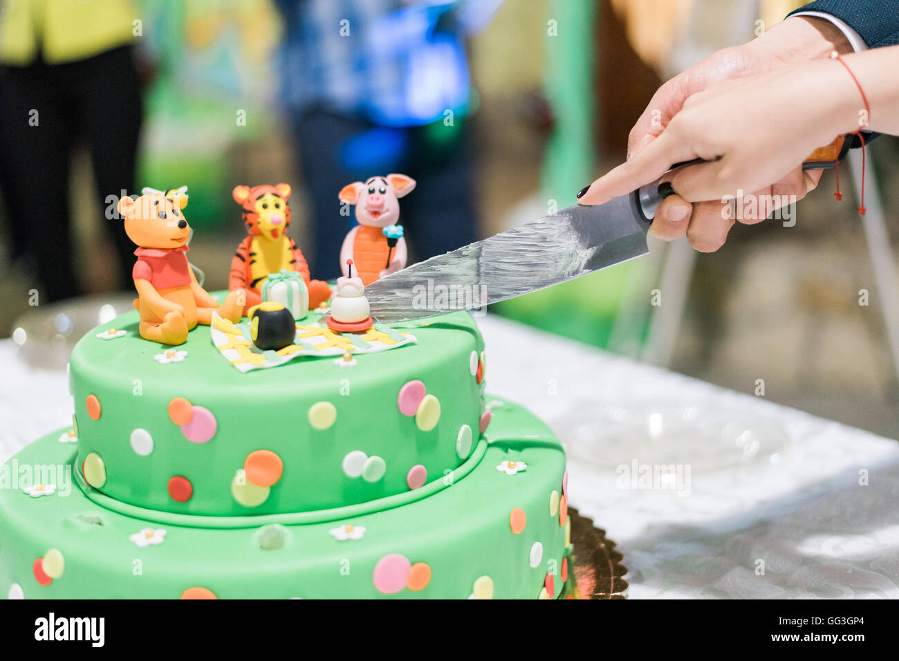 Slicing the Birthday cake with candles and Winnie the Pooh by Disney Stock Photo