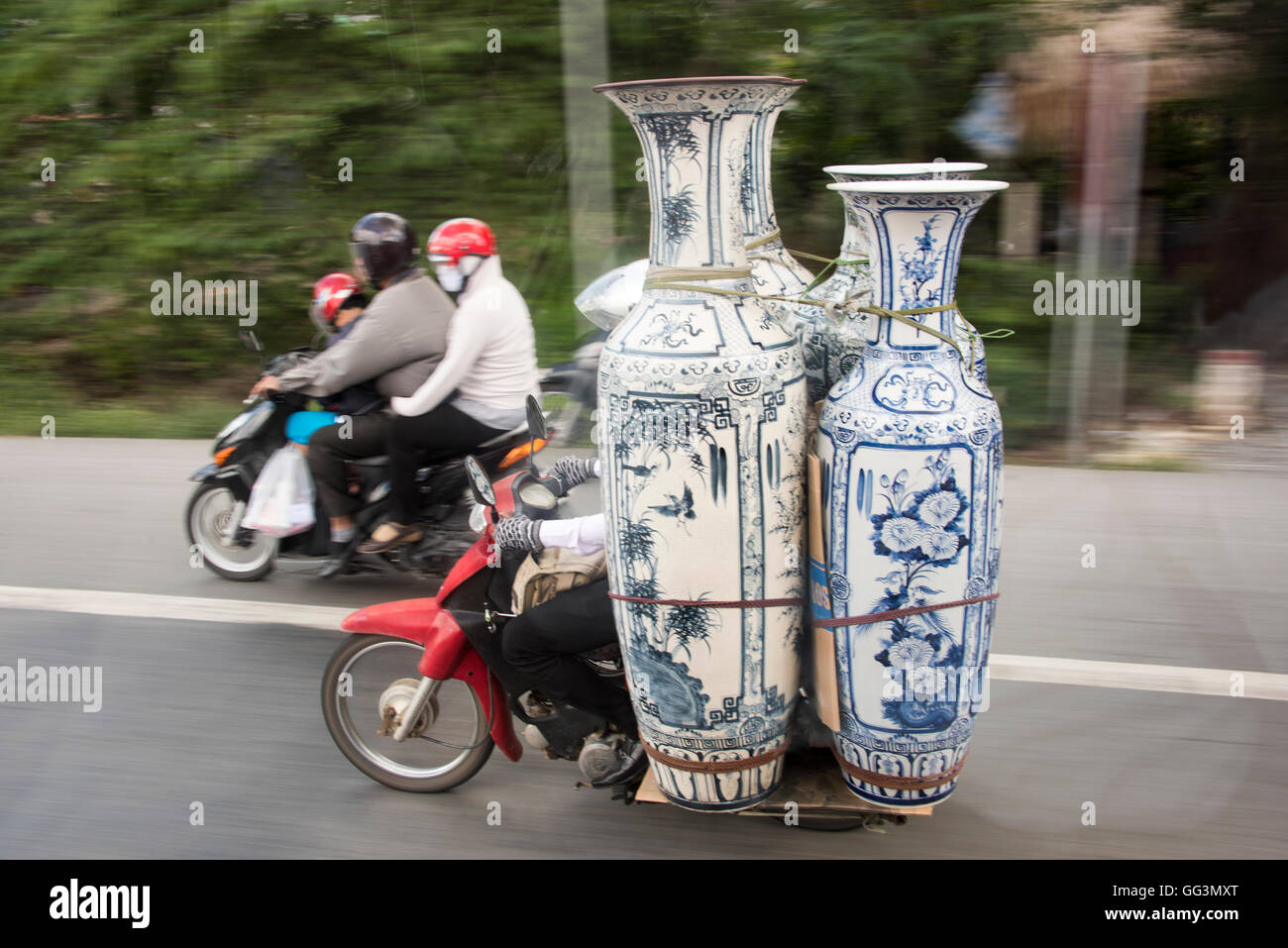 Motorbike carrying vases on the street of Vietnam, near Saigon, also family of three on another motorbike. Typical street scene Stock Photo