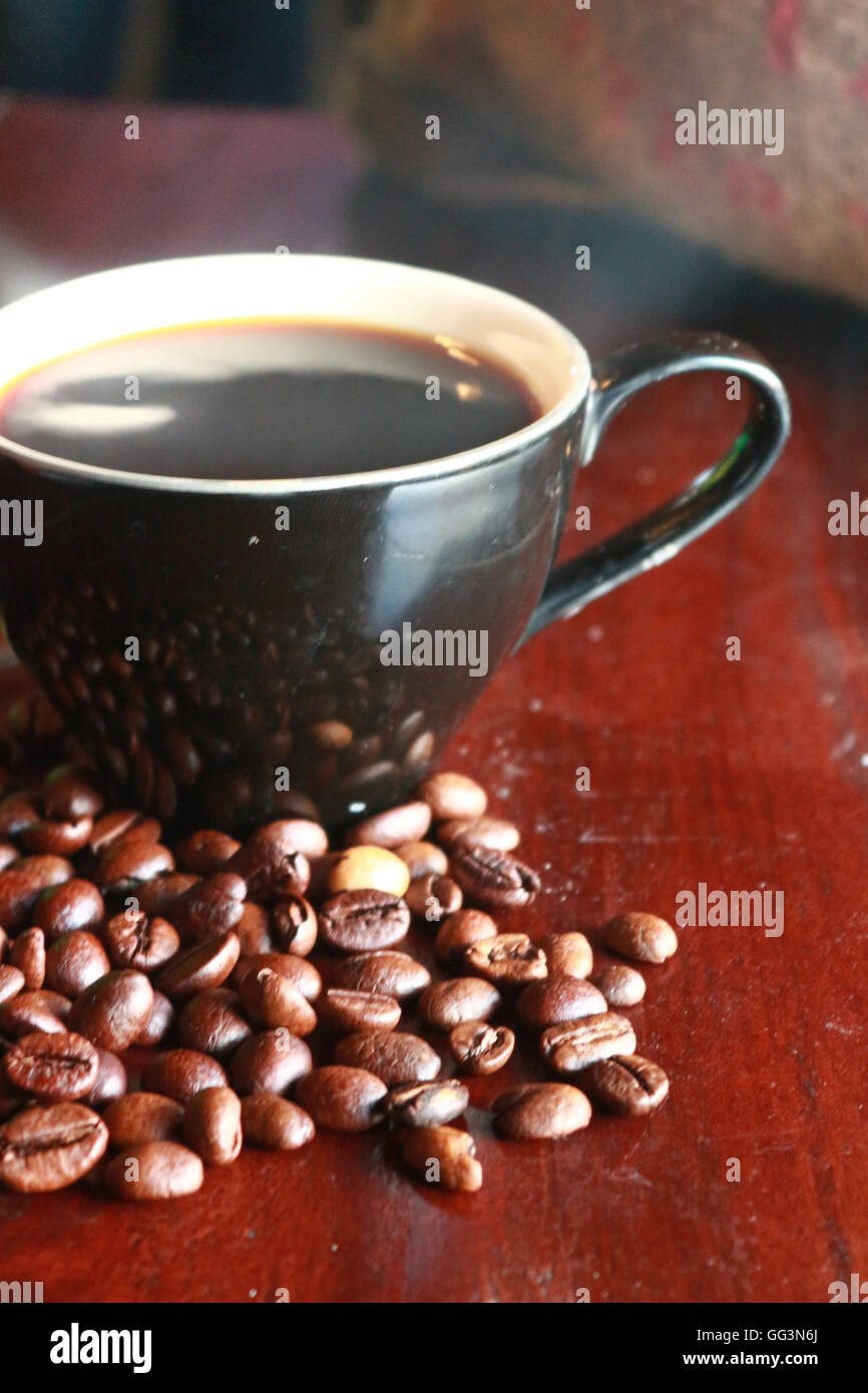 Hot Coffee Cup With Coffee Beans On The Table Stock Photo