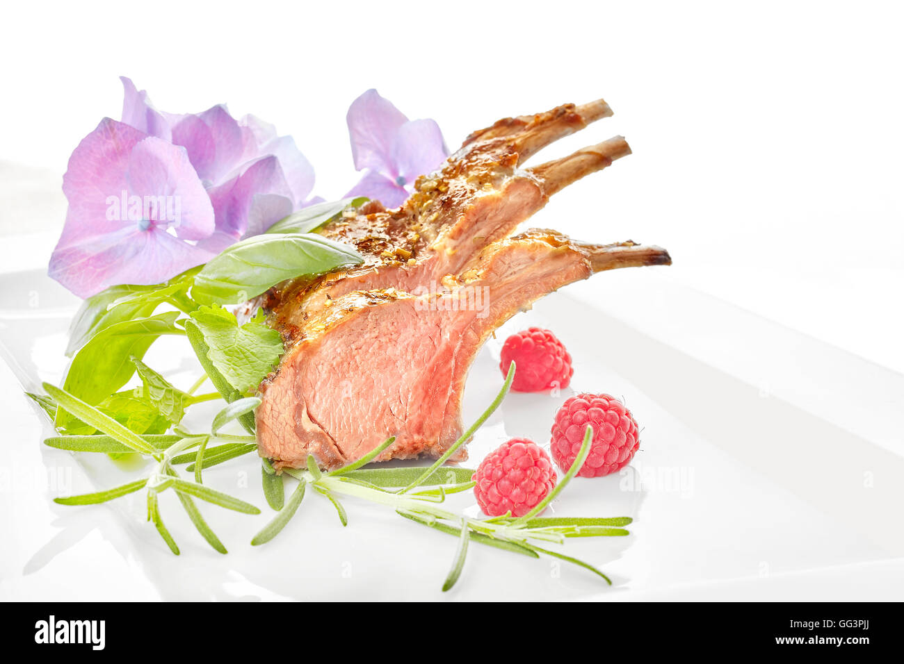 Roasted lamb rib chops with raspberries on a plate, dinner setting. Stock Photo