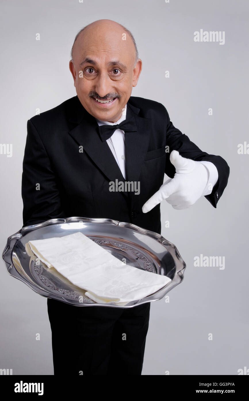 Butler gesturing to serving tray Stock Photo