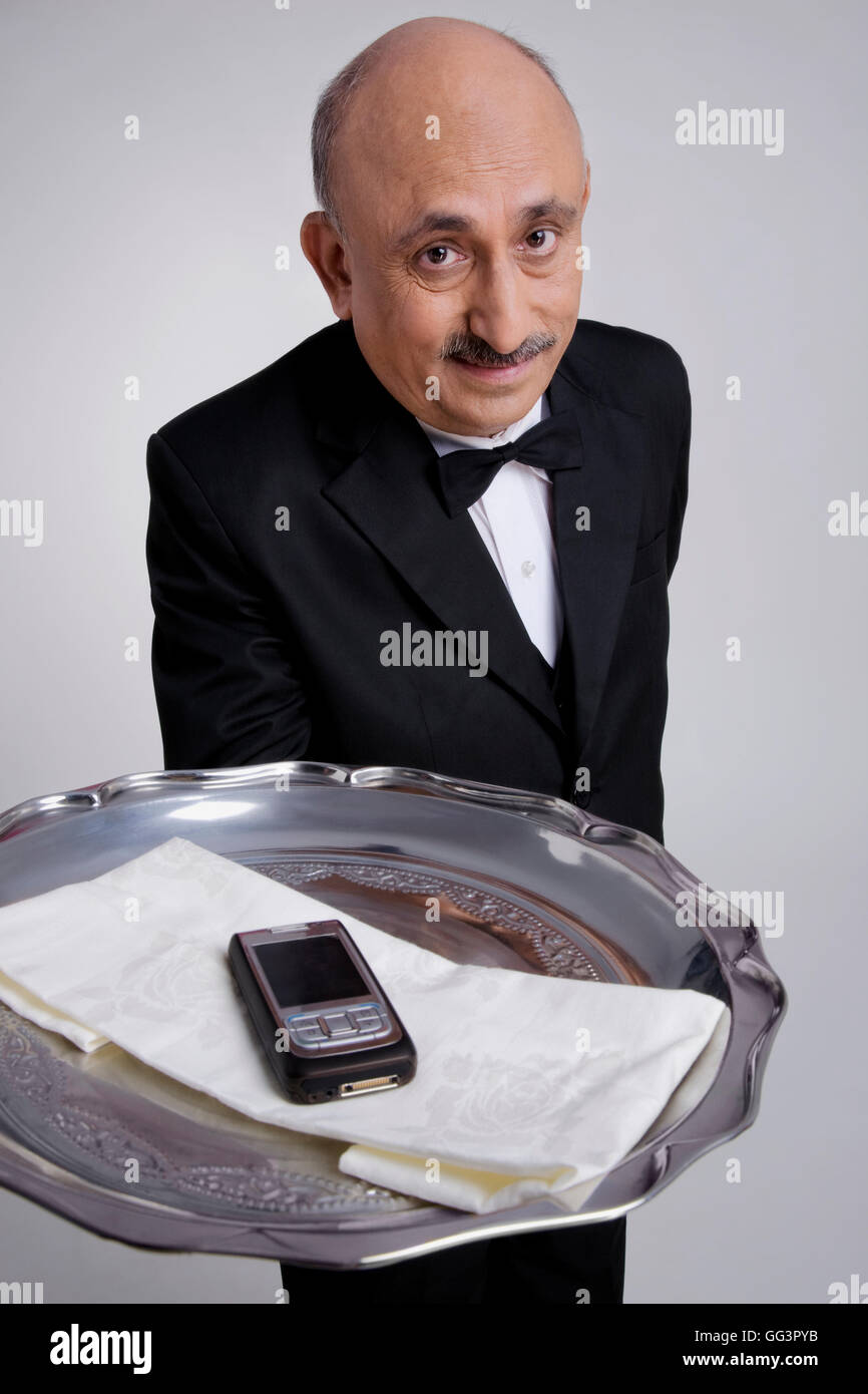 Butler serving a mobile phone Stock Photo