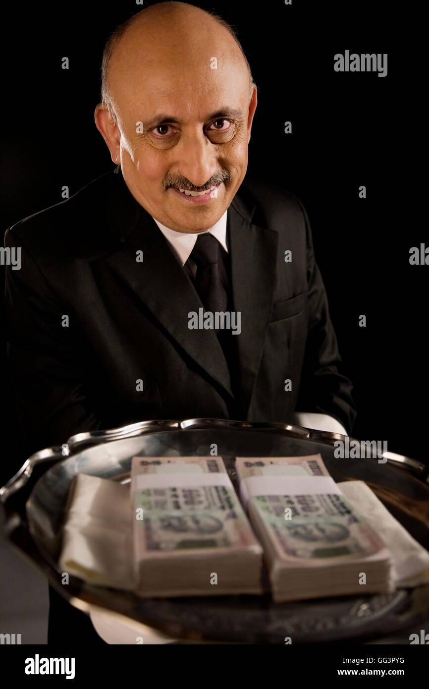 Butler serving money on a tray Stock Photo