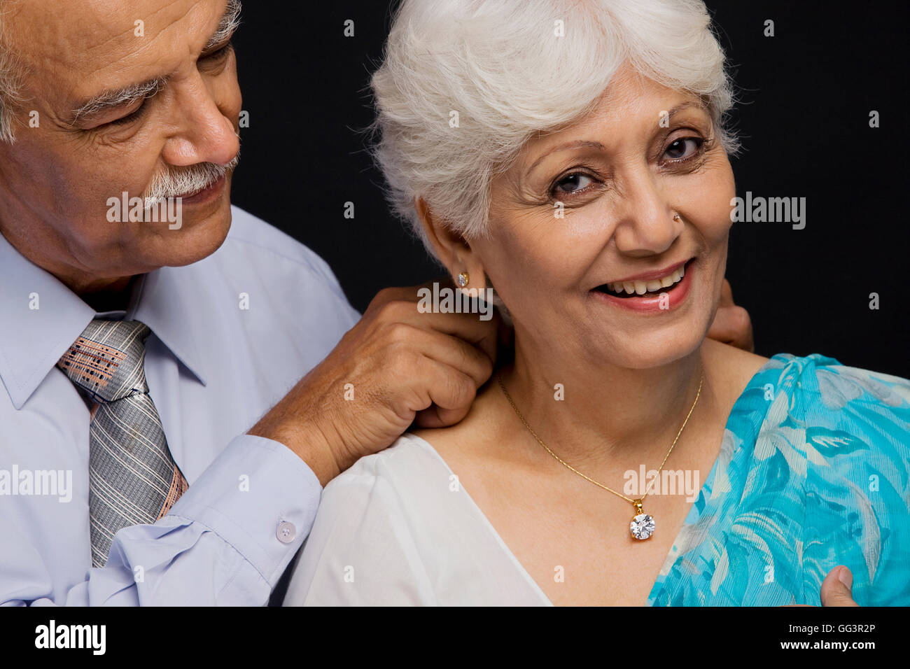 Man putting a necklace around her neck Stock Photo
