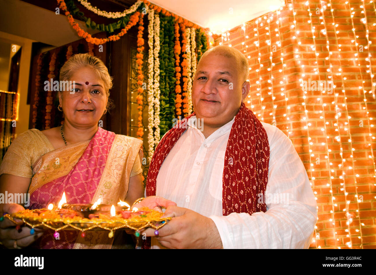 Old couple holding a tray of diyas Stock Photo
