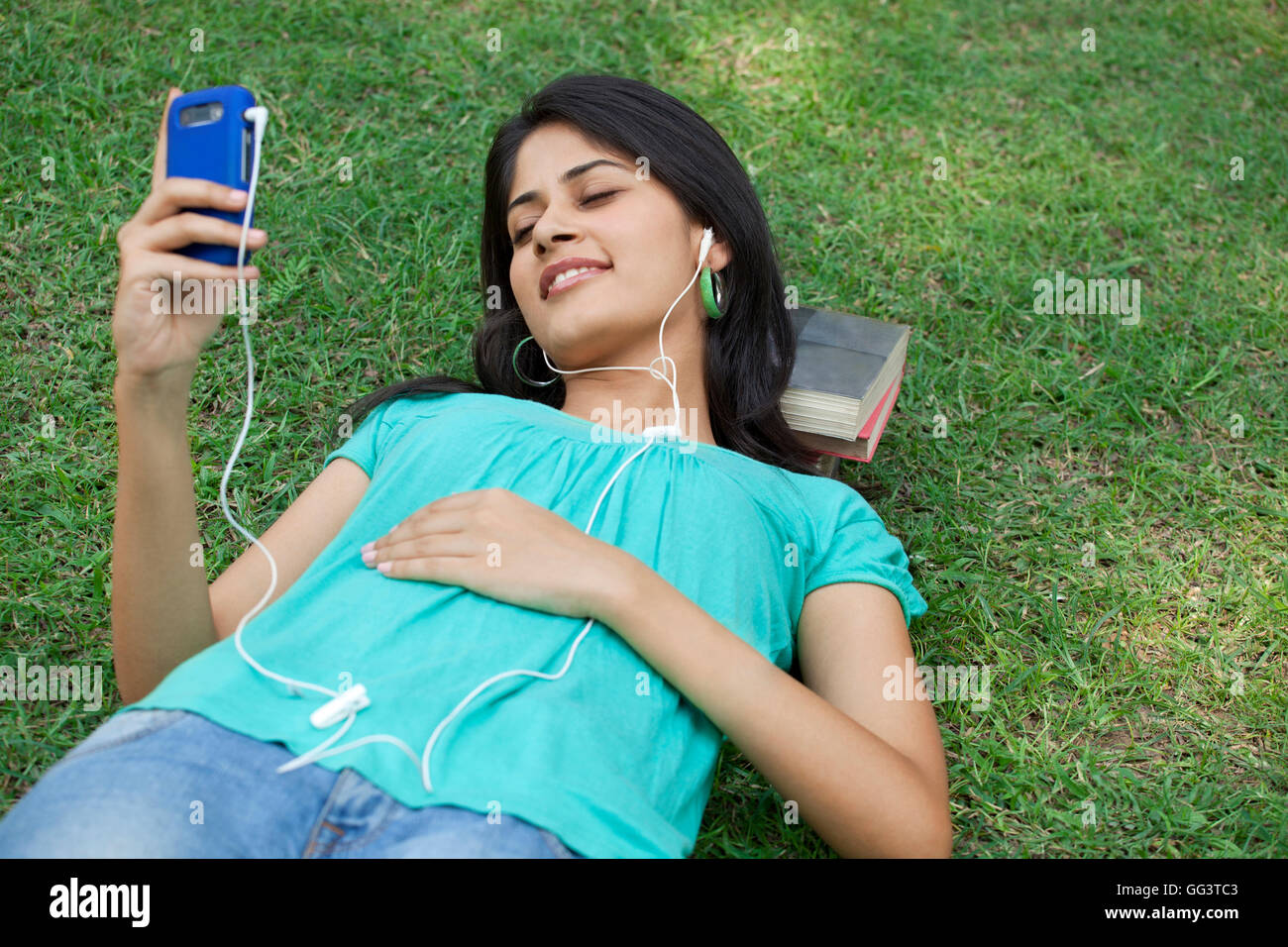 Woman lying on grass listening to mp3 player Stock Photo - Alamy