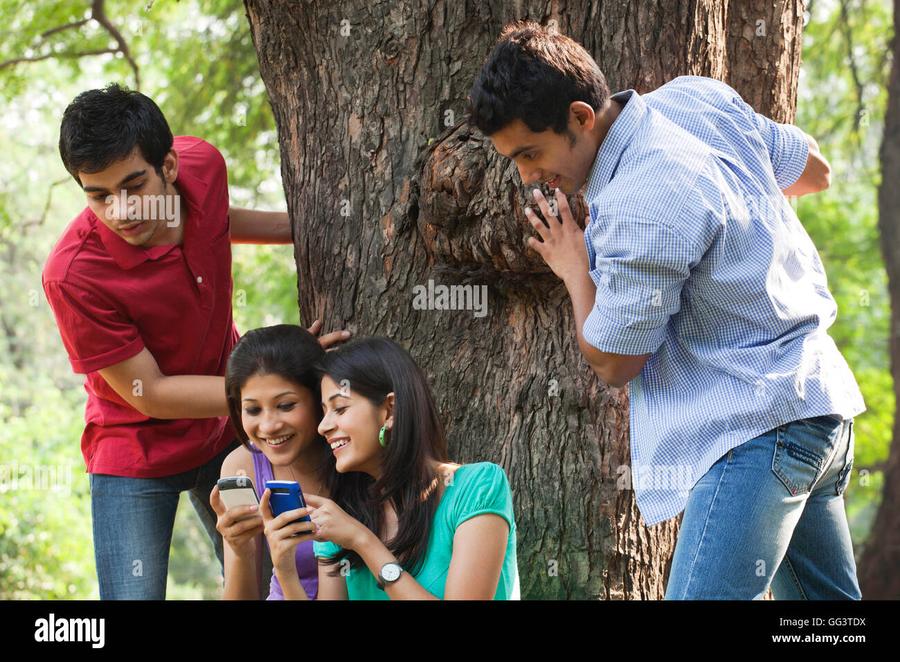 Women sharing messages while men peeking from behind Stock Photo