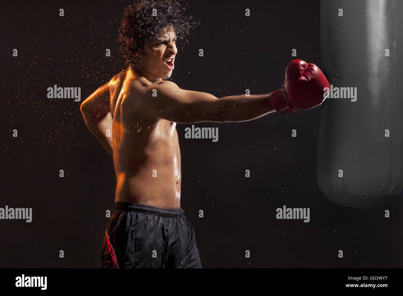 Male boxer hitting punching bag over black background Stock Photo Alamy