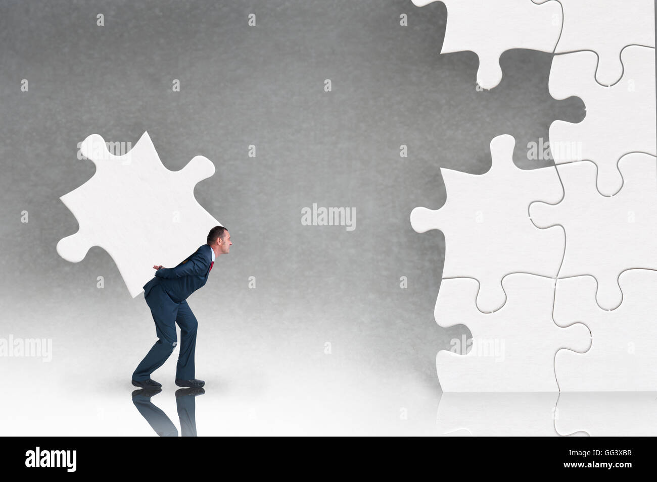 business puzzle concept businessman working to complete a jigsaw Stock Photo