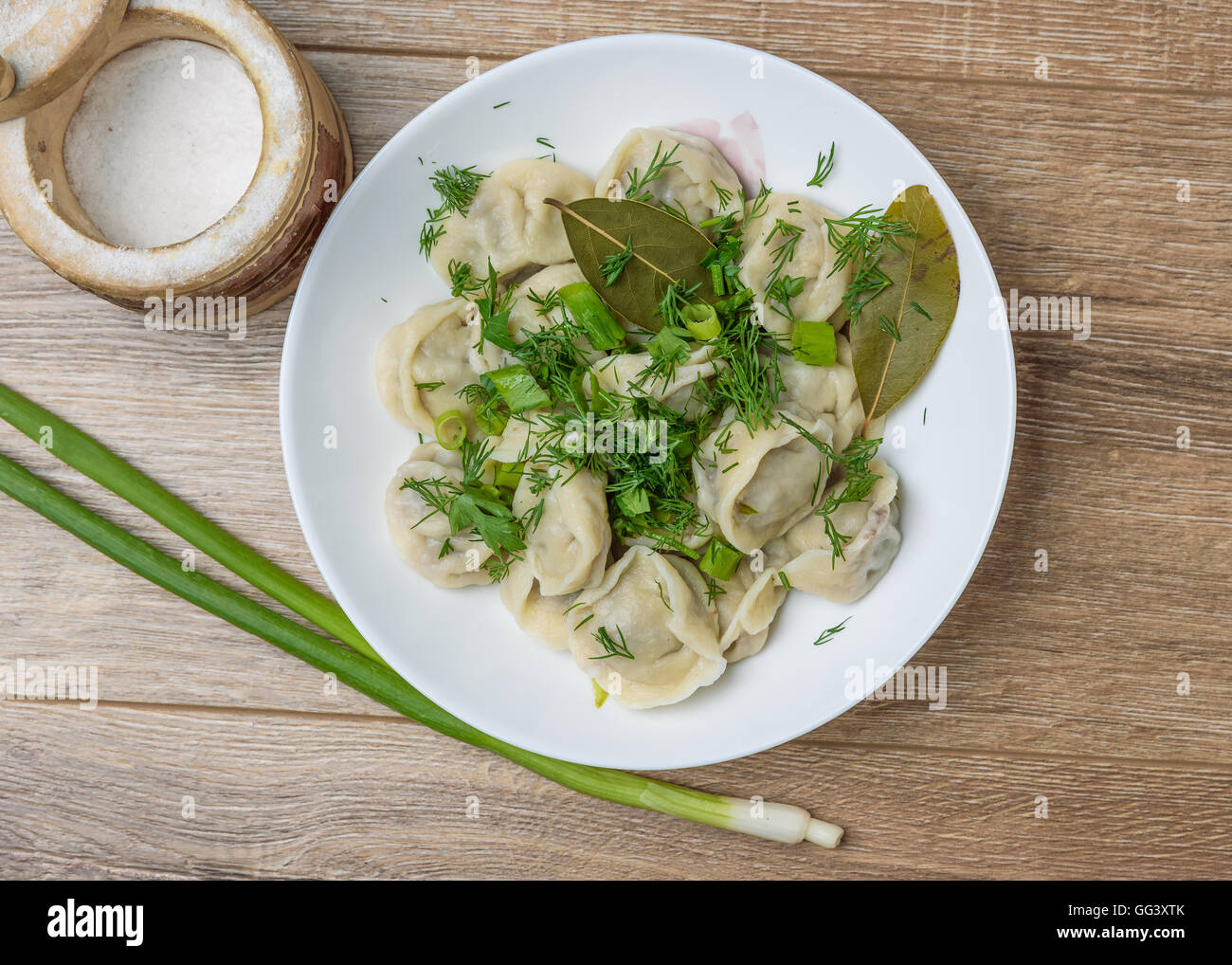 plate of traditional Russian dumplings sprinkled with herbs on a wooden table Stock Photo