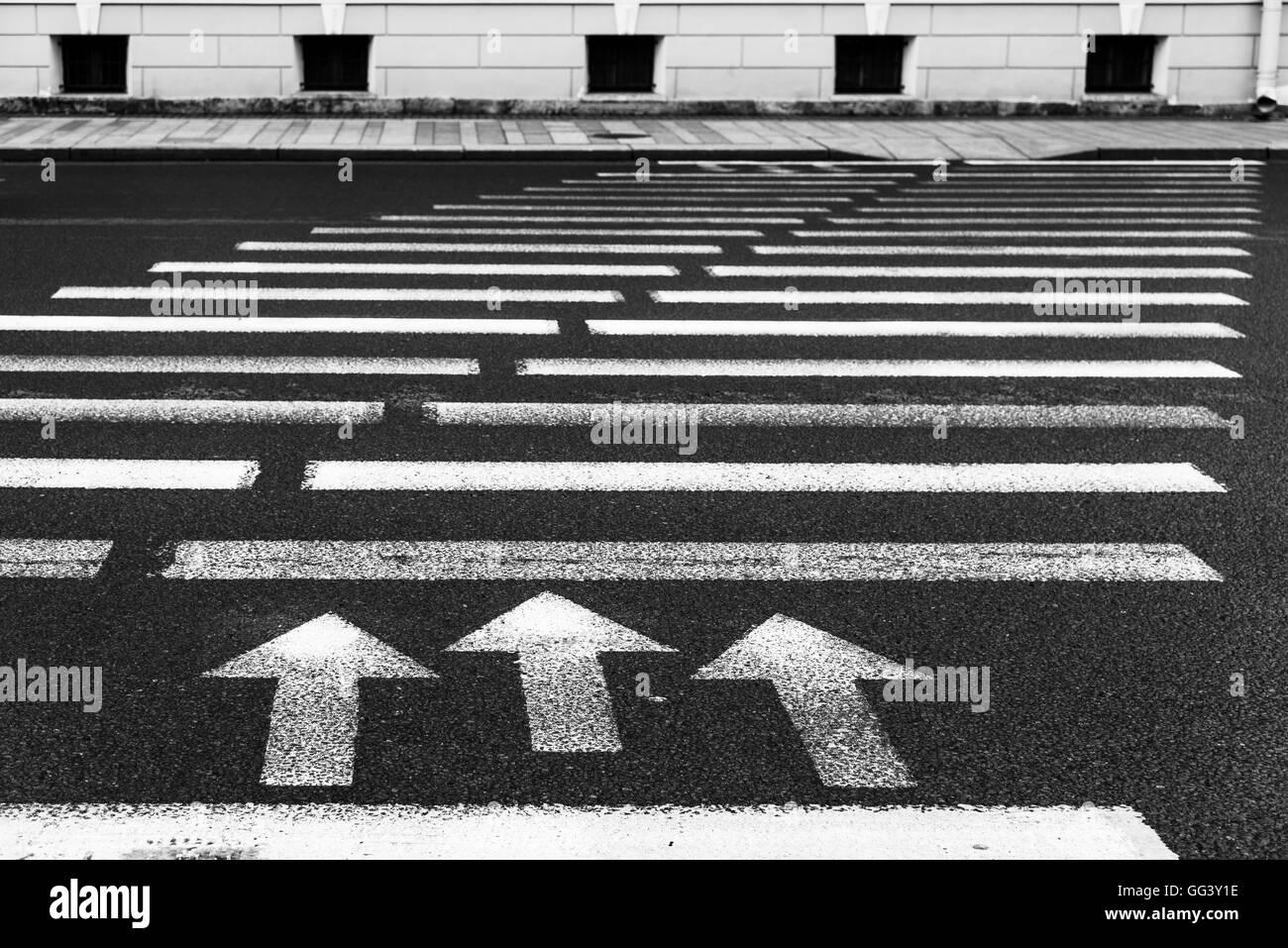 Pedestrian crossing with road marking: white arrows and rectangles on dark asphalt Stock Photo