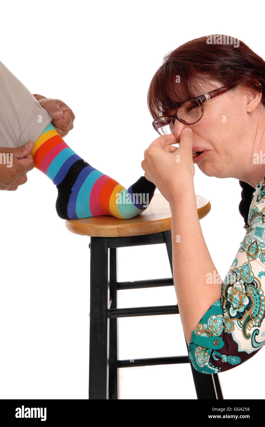 A discussed woman holding her nose closed from the smell of her husband's socks, isolated for white background. Stock Photo