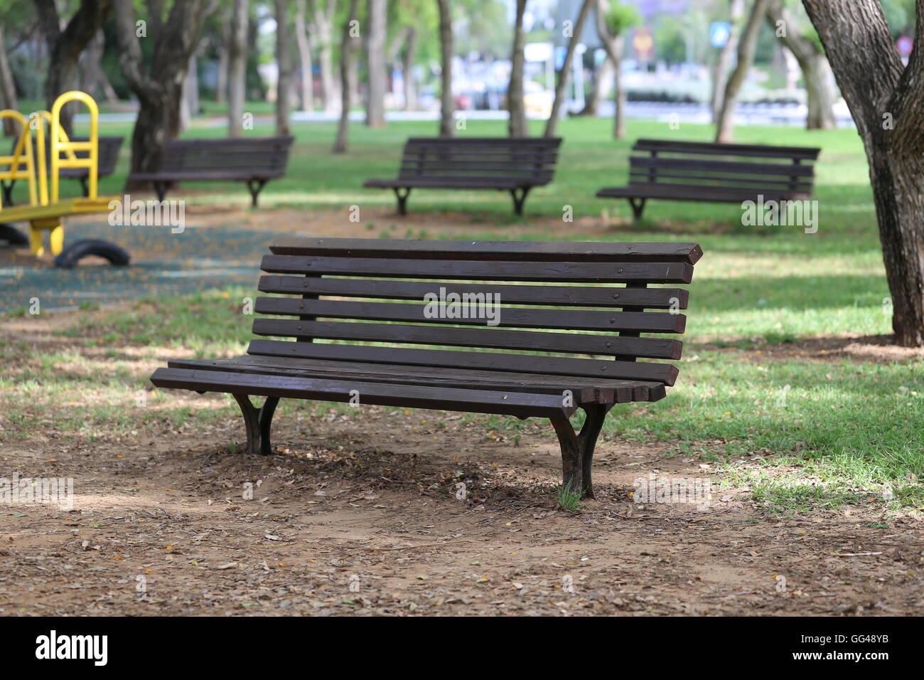 Park Benches. Public park benches in the shady grove. Wooden benches in the park near playground toys. Stock Photo