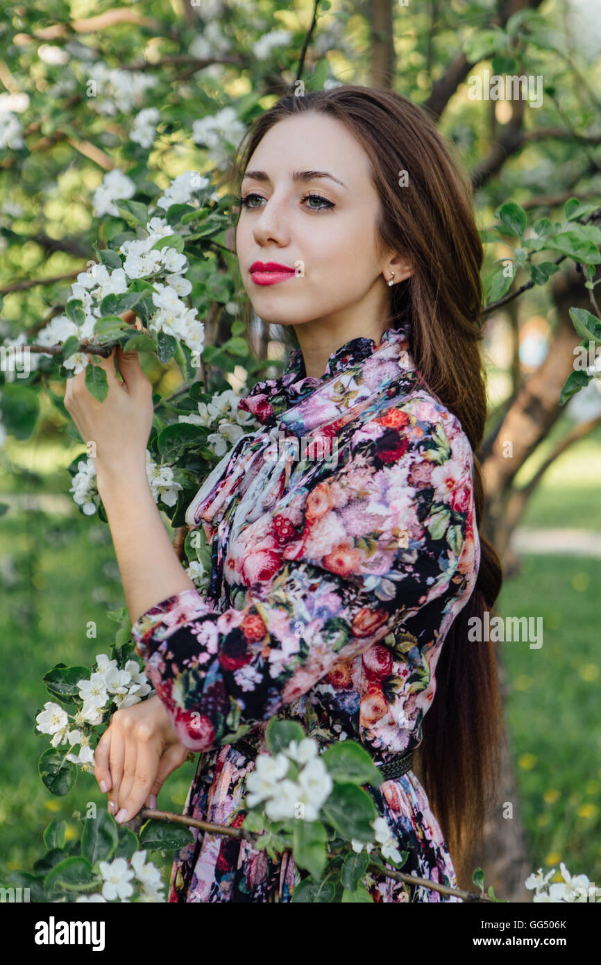 Beautiful young woman in dress standing near the blooming apple tree ...