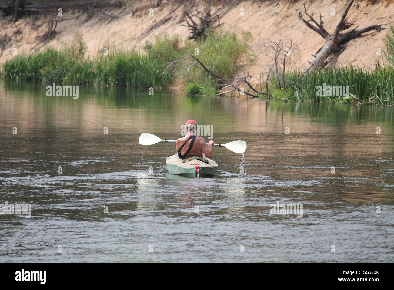 strong sunburn man into sport canoe with paddle get wild travel in summer on river Viliay, 27, 2016, Belarus Stock Photo