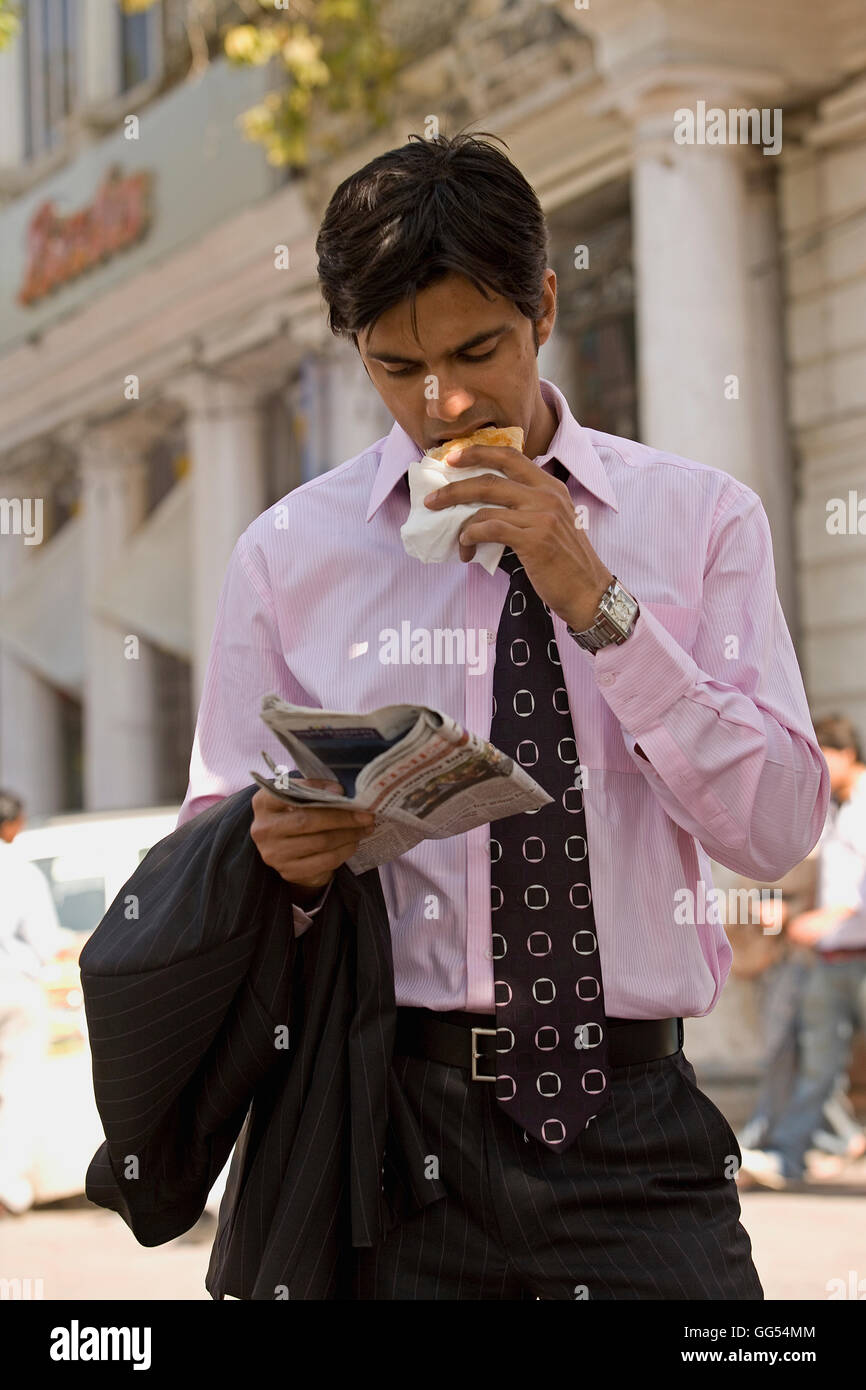 Man eating while reading a newspaper Stock Photo Alamy
