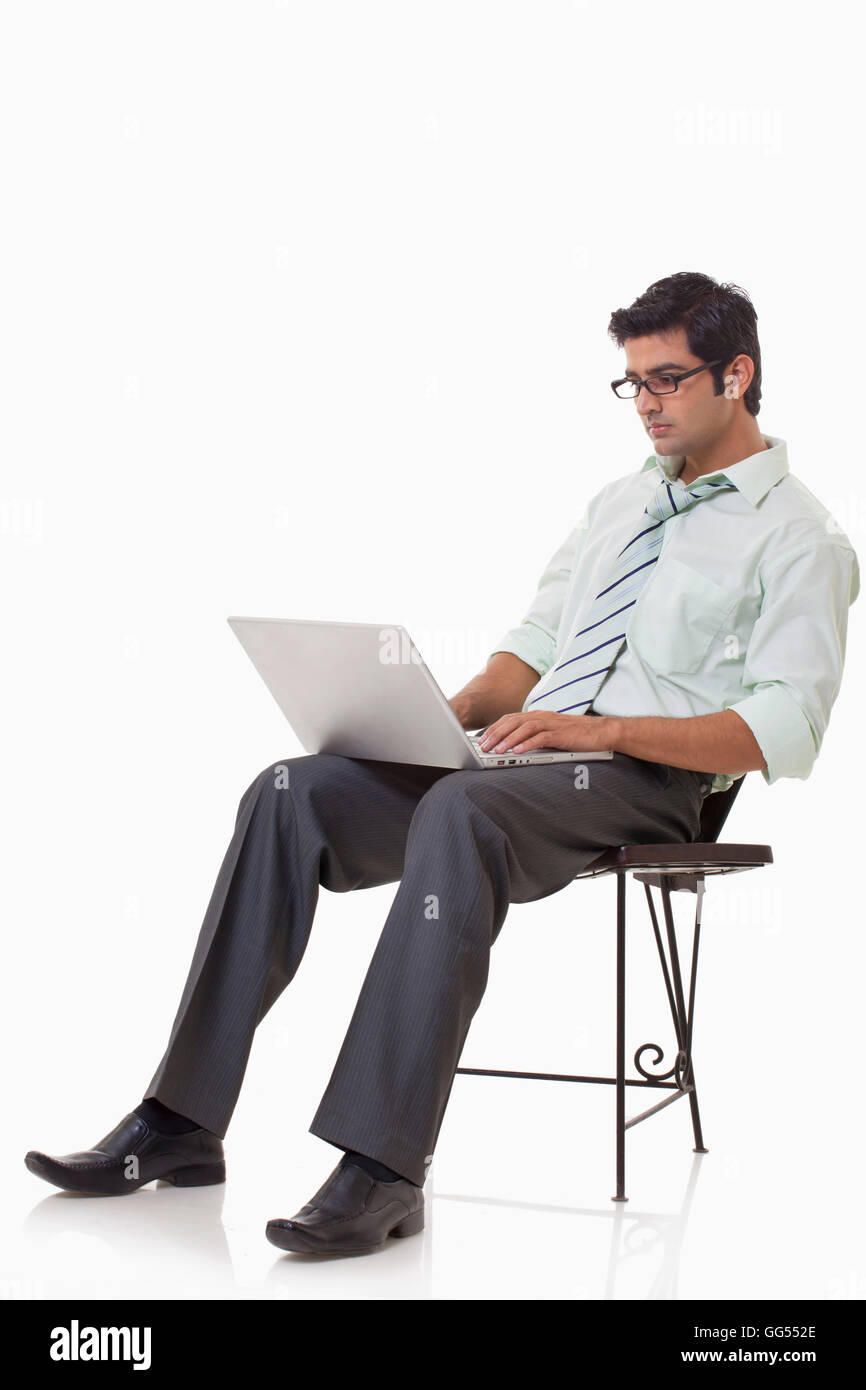 Male executive sitting on chair with laptop Stock Photo - Alamy