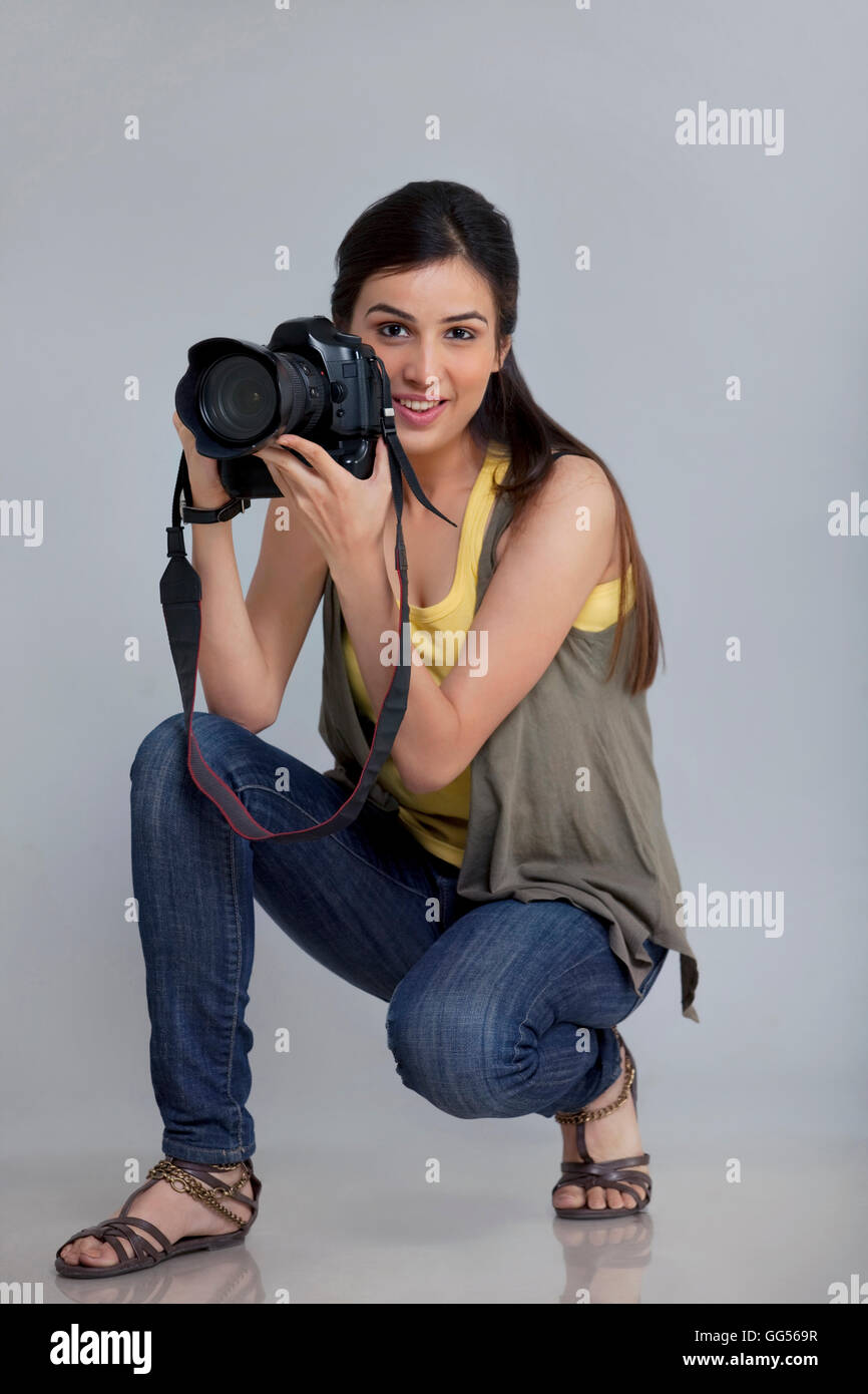 Full length of smiling female photographer with camera in her studio ...