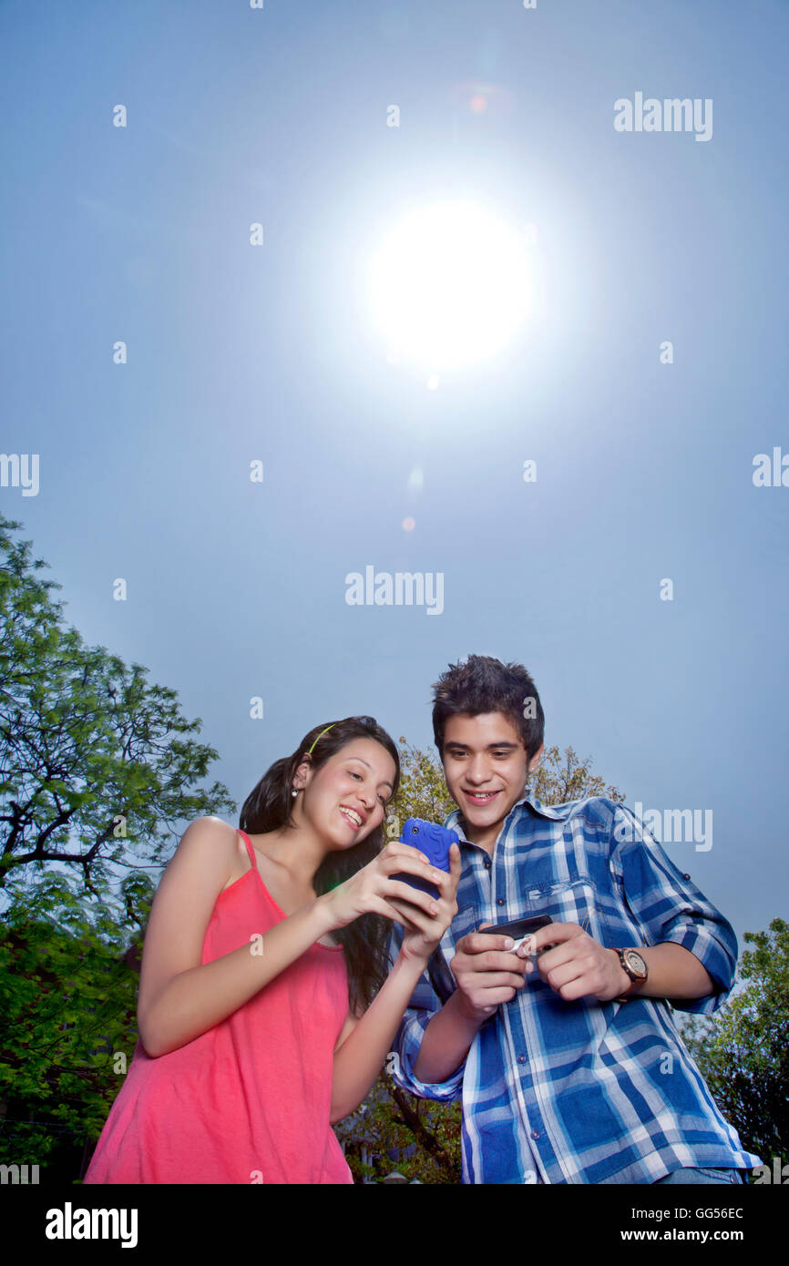 Low angle view of man and woman using cell phone Stock Photo