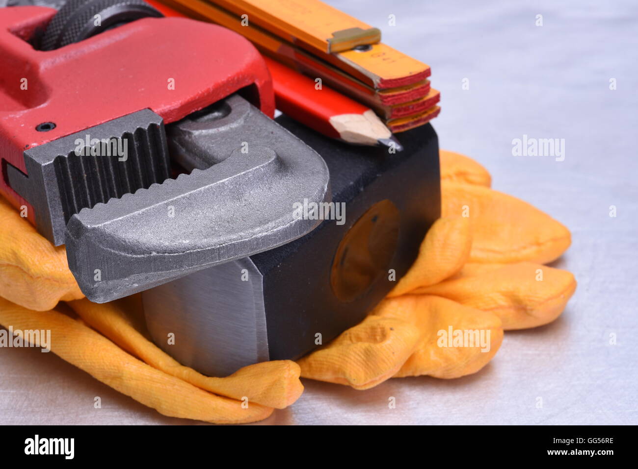 Closeup hand working tools pipe wrench and hammer on metal surface
