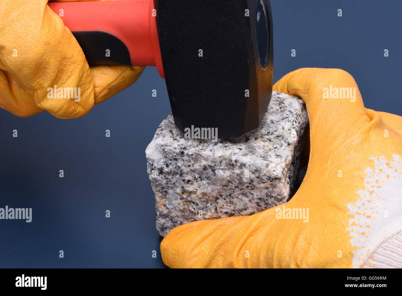 Close-up of hand holding hammer and stone block Stock Photo
