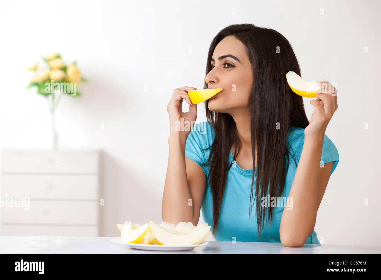 Young woman eating melon at home Stock Photo Alamy
