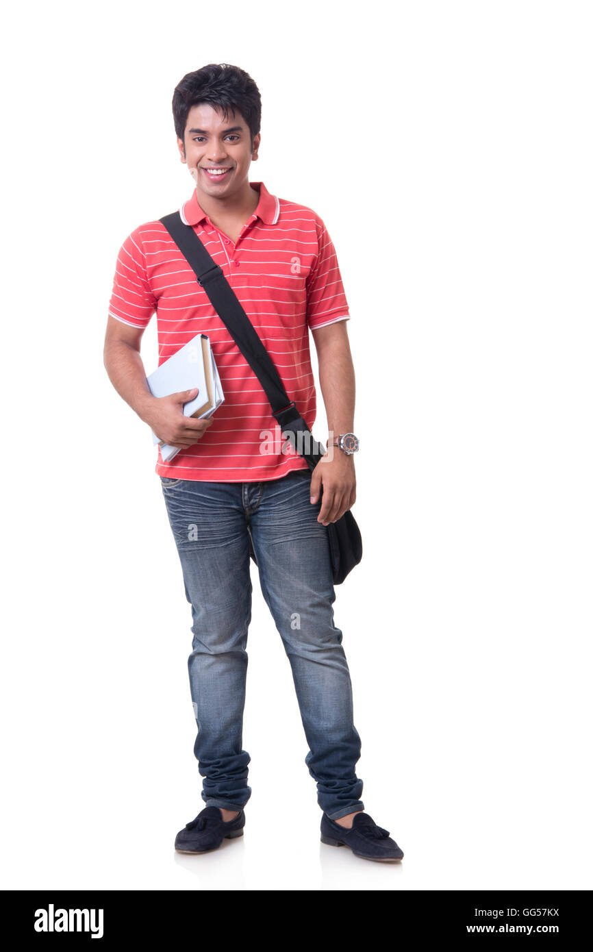 Full length portrait of smiling male student with books and bag against ...