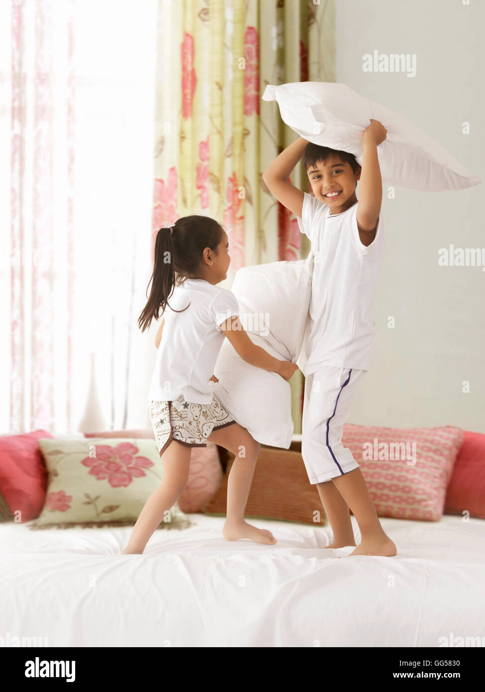 Playful siblings having pillow fight on bed Stock Photo - Alamy