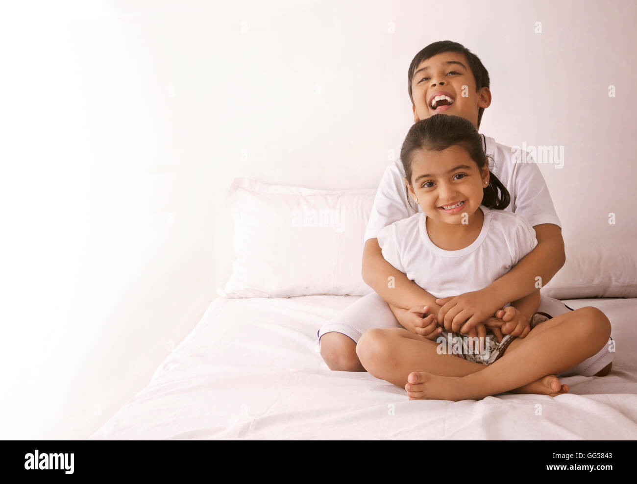Portrait of happy girl being embraced by brother in bed Stock Photo