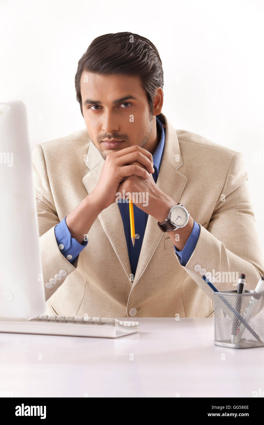 Portrait of confident young businessman at computer desk Stock Photo