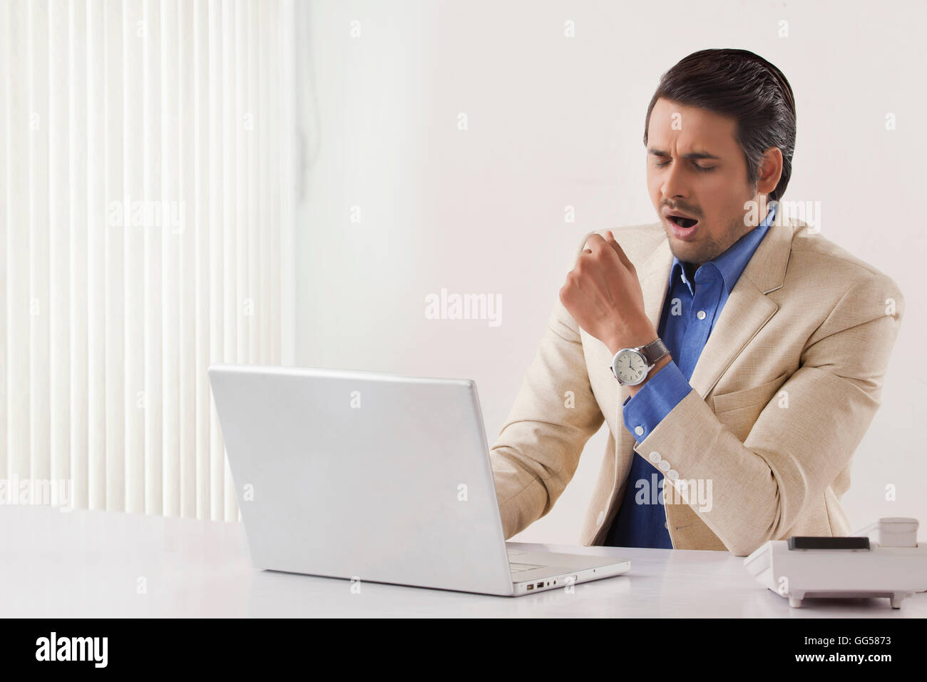 Exhaustion young businessman using laptop at office desk Stock Photo