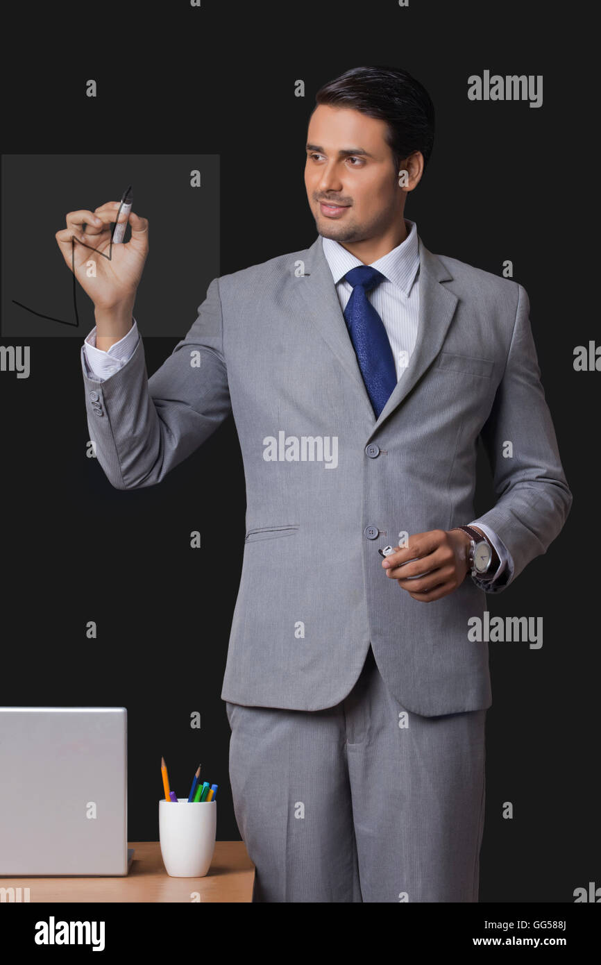 Young Indian businessman drawing graph on transparent screen Stock Photo