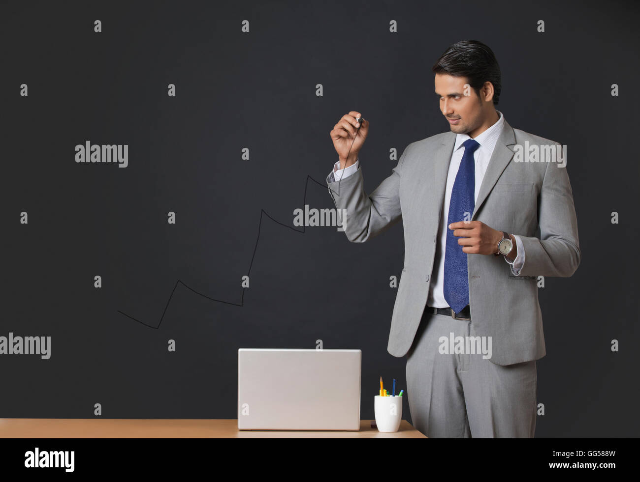 Young Indian businessman drawing graph on transparent screen at office Stock Photo