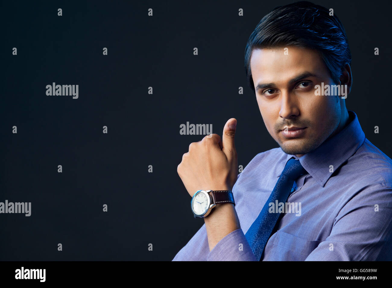 Portrait of confident young businessman over black background Stock Photo
