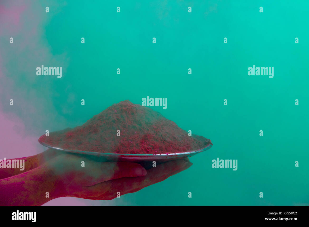 Close-up of hands holding plate with pink color powder during Holi festival Stock Photo