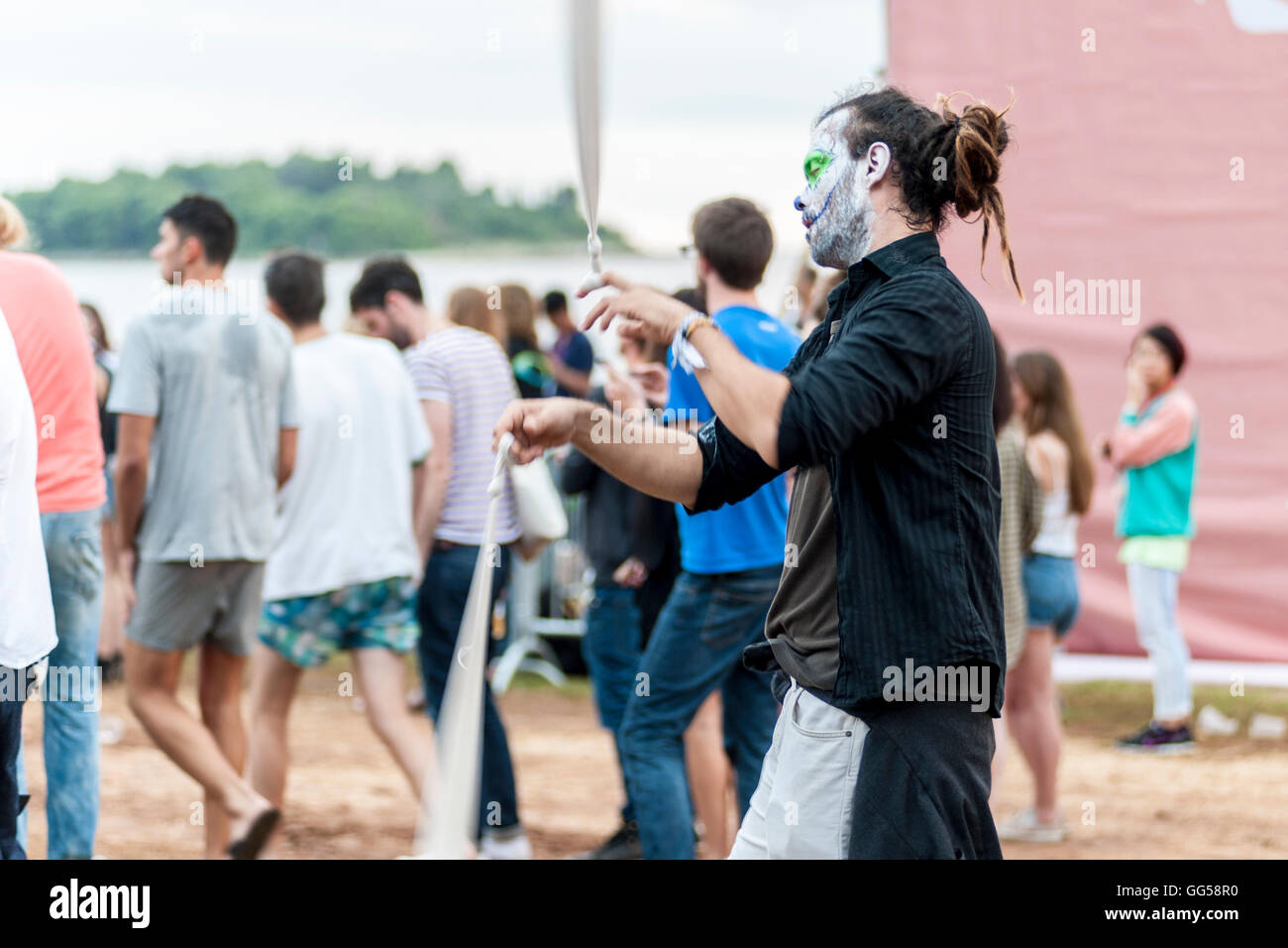 A young man with painted face and closed eyes is dancing on a music festival in a seaside town of Rovinj in Croatia. Stock Photo