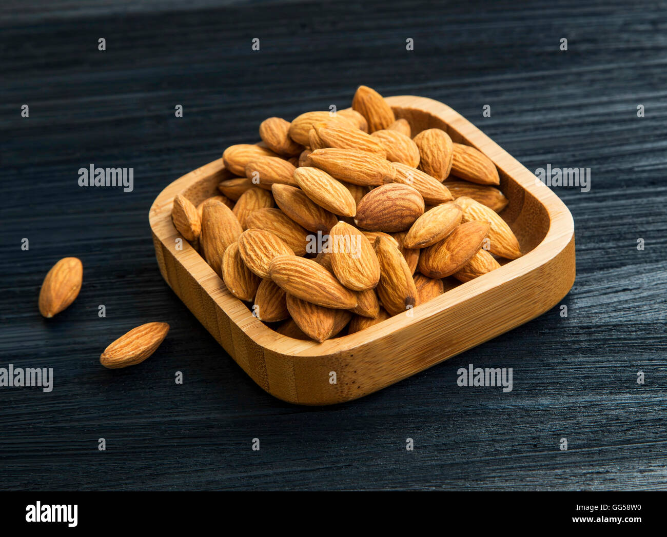 Fresh almonds nuts in wooden bamboo bowl , healthy brown nuts Stock Photo