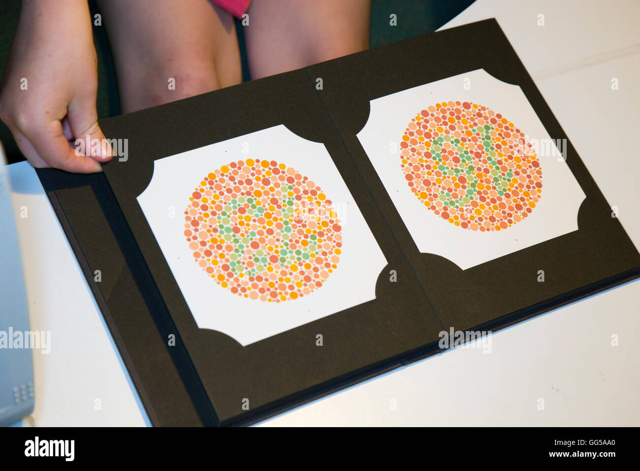 Colour blindness / Color blind test card: child holding test book / books / sheet / number sheets for Colour Blindness. Stock Photo